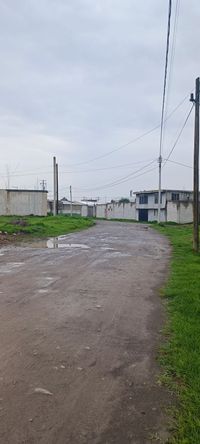 Acceso principal al terreno con calle de terracería y postes de luz