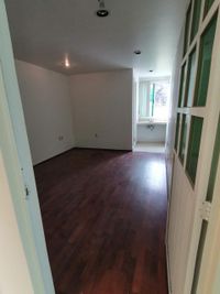 Consultorio u oficina privada con piso de madera y ventana al exterior en edificio de tres niveles en Toluca.